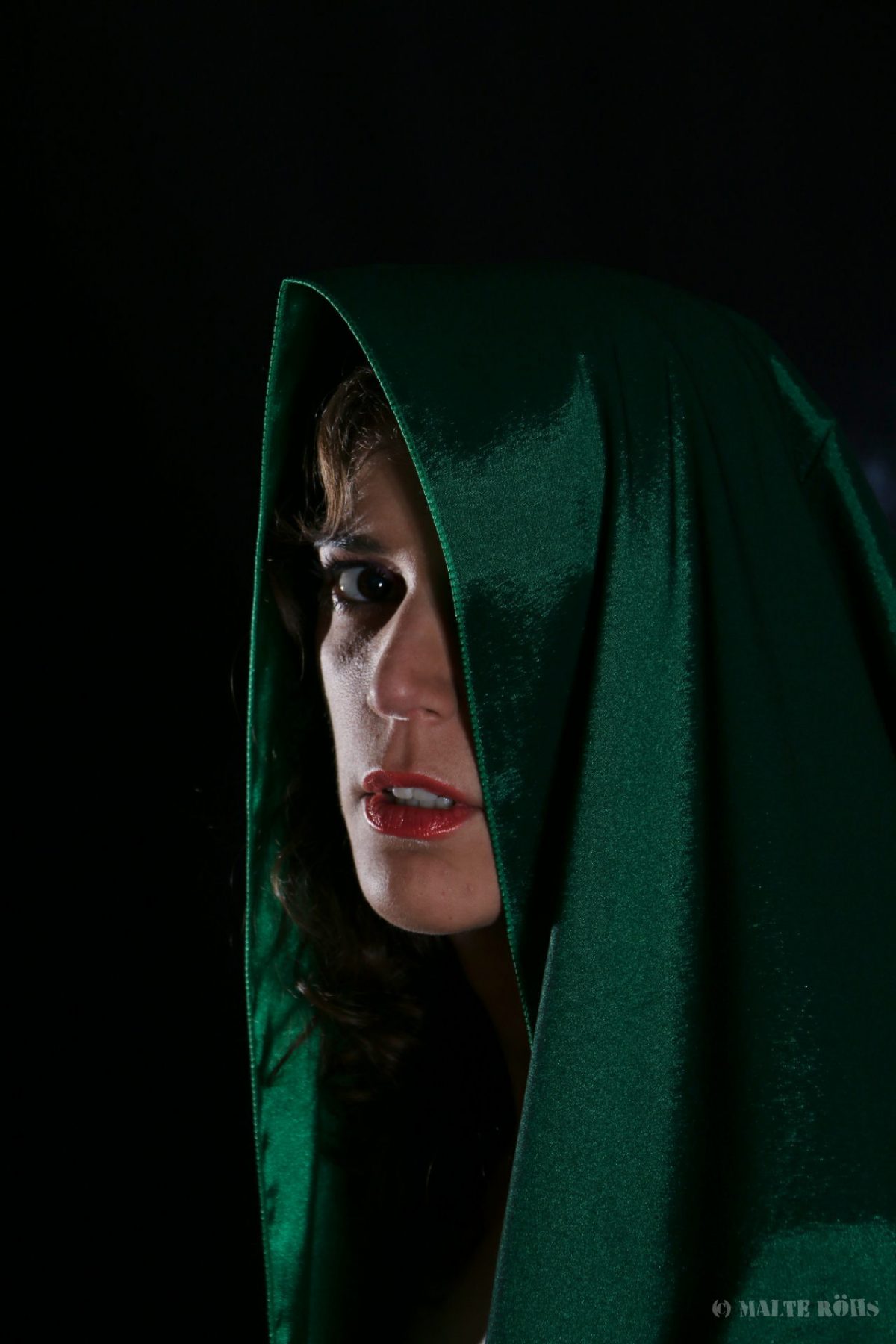 Low-Key portrait of a beautiful woman waring a green silk hood